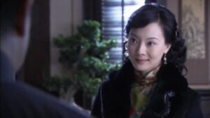 中国の女優チェン・シューが緑地の花柄旗袍と黒のコートを着ている場面。