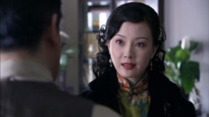 中国の女優チェン・シューが緑地の花柄旗袍と黒のコートを着ている。
