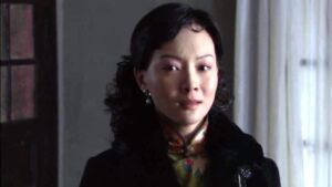 中国の女優チェン・シューが緑地の花柄旗袍と黒のコートを着ている場面。