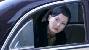 中国の女優チェン・シューが緑地の花柄旗袍と黒のコートを着ている場面。タクシーから顔を出している。