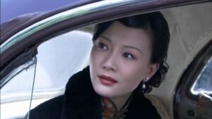 中国の女優チェン・シューが緑地の花柄旗袍と黒のコートを着ている場面。タクシーから外を覗いている。