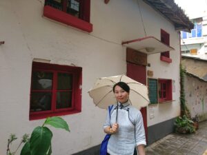 中国昆明市にある文化巷という街で、チャイナ服を着たレイレイが日傘をさしている写真。