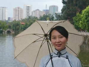 中国昆明市にある翠湖で、チャイナ服を着たレイレイが日傘をさしている写真。