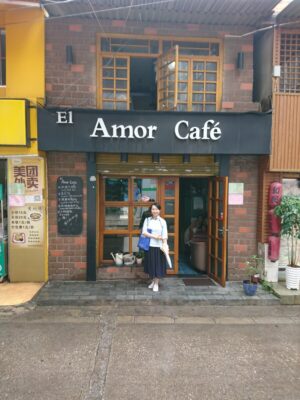 中国昆明市のAmor Cafeというカフェの前でチャイナ服を着てレイレイが立っている写真。