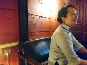 中国昆明市の文化巷にあるサルバドールカフェで、チャイナ服を着たレイレイが笑っている写真。