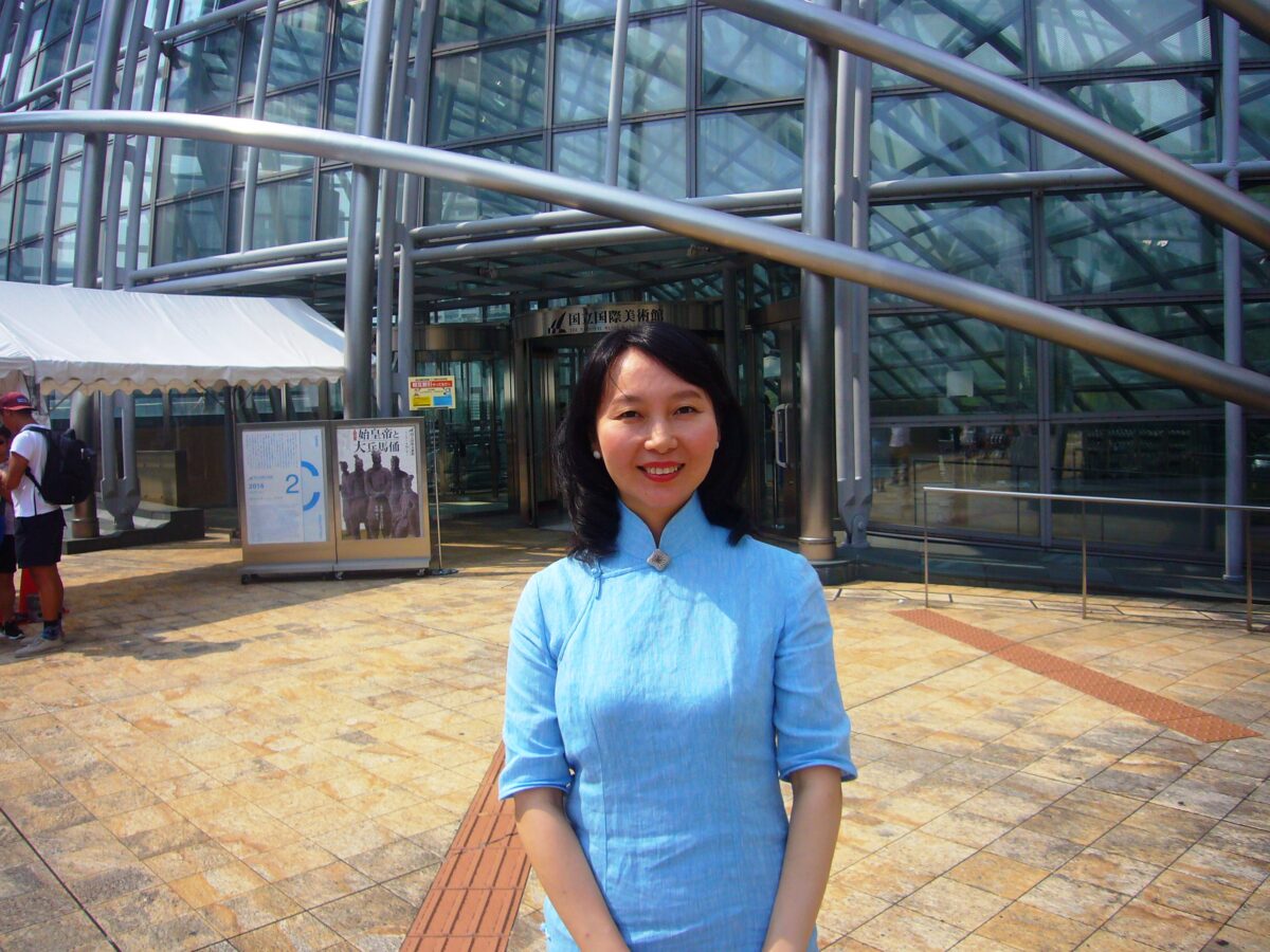 大阪国立国際美術館の前で、チャイナドレスを着たレイレイが笑っている写真。
