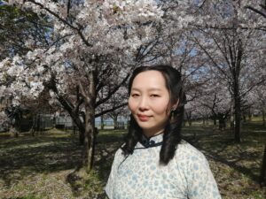 桜が満開の公園でチャイナドレスを着ているレイレイ。
